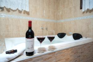 a bottle of wine and two wine glasses on a bath tub at Chalés Valle Florido in Monte Verde