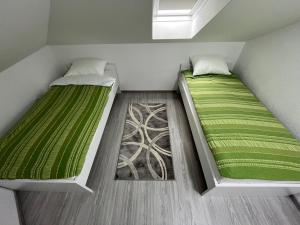 duas camas num pequeno quarto com lençóis verdes em The View Apartment Sarajevo em Sarajevo