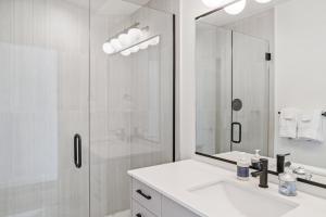 a white bathroom with a shower and a sink at Modern two story townhouse near light rail in Seattle