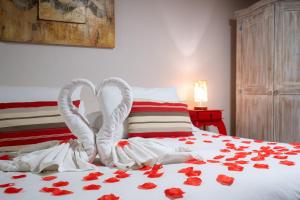 1 cama con rosas rojas y toallas y corazones blancos en Chalés Valle Florido, en Monte Verde