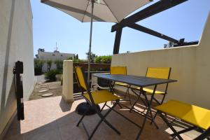 - une table et des chaises sur une terrasse avec un parasol dans l'établissement Studio Naturiste "JUL'S"Port Nature 401, au Cap d'Agde