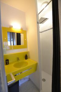 La salle de bains est pourvue d'un lavabo jaune et d'un miroir. dans l'établissement Studio Naturiste "JUL'S"Port Nature 401, au Cap d'Agde