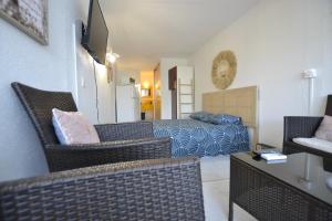 a living room with a bed and wicker chairs at Studio Naturiste "JUL'S"Port Nature 401 in Cap d'Agde