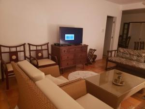 a living room with a couch and a tv at Secret Spot Floripa in Florianópolis