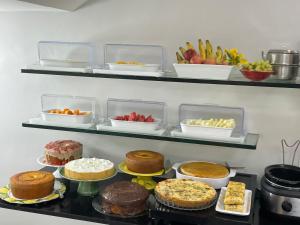 a shelf filled with different types of cakes and pastries at Bianca Praia Hotel in Recife