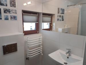 a white bathroom with a sink and a mirror at Domki Oaza Spokoju in Władysławowo