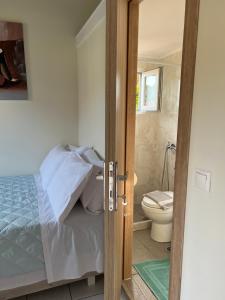 bagno con letto e servizi igienici in camera. di Vasiliki Little House a Kanoni