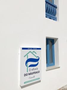 un panneau sur le côté d'un bâtiment avec une fenêtre dans l'établissement O Refuxio do Náufrago, à Camelle