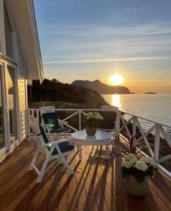 a balcony with a table and chairs and the sunset at Aalesund Oceanview in Ålesund