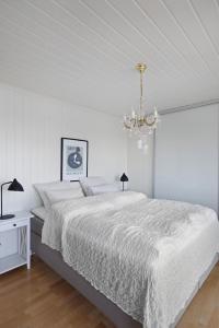 a white bedroom with a bed and a chandelier at Aalesund Oceanview in Ålesund