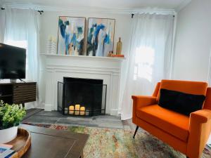 a living room with an orange chair and a fireplace at Large Renovated Cottage on East Lake Park in Birmingham