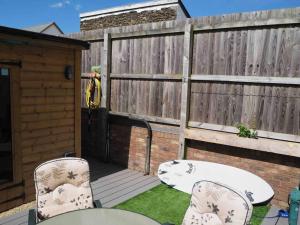 a patio with two chairs and a table and a fence at Braunton Breaks - South Break House in Braunton