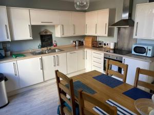 a kitchen with white cabinets and a table with chairs at Braunton Breaks - South Break House in Braunton
