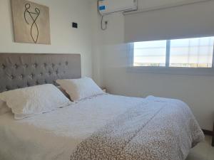 een slaapkamer met een bed met witte lakens en een raam bij Vinum apart in Godoy Cruz