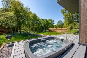 a hot tub on a wooden deck with a yard at The Stag, Luxury pod with hot tub, Croft4glamping in Oban