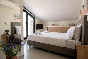 a bedroom with a large white bed and a window at Agro Nostro-Euphorbia two bedroom house in Agios Nikolaos