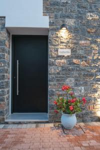 a black door with a plant next to a brick wall at Agro Nostro-Euphorbia two bedroom house in Agios Nikolaos