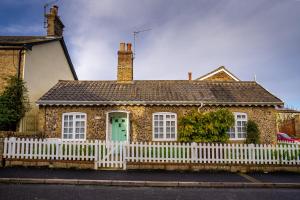 a house with a white fence in front of it at All Seasons Cottage Breaks in Saxmundham