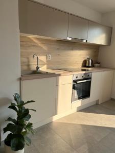 a kitchen with white cabinets and a sink and a stove at Luni in Zadar
