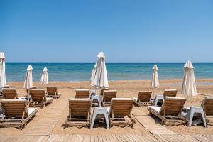 een groep stoelen en parasols op een strand bij Esperides Beach Hotel Apartments in Stalós