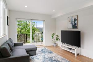 a living room with a couch and a flat screen tv at Modern two story townhouse near light rail in Seattle