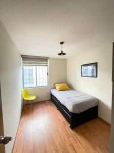1 dormitorio con 1 cama y 1 silla amarilla en Departamento en Centro Ciudad de México Alameda Reforma en Ciudad de México