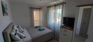 - une chambre avec un lit et une télévision à écran plat dans l'établissement Apartments Toni, à Rogoznica