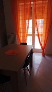 mesa de comedor con cortinas naranjas y ventana en la mia casetta, en Bisceglie