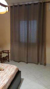 1 dormitorio con 1 cama y una ventana con cortinas en la mia casetta, en Bisceglie
