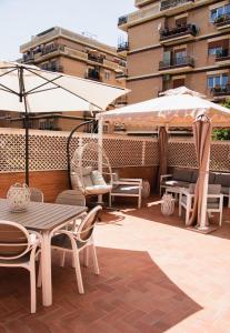 een patio met een tafel, stoelen en parasols bij Mausida Guest House in Lido di Ostia