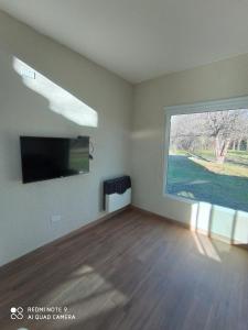 ein Wohnzimmer mit einem großen Fenster und einem Flachbild-TV in der Unterkunft DelViento Cabañas in Las Rabonas