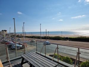 a wooden bench on a balcony with a view of the beach at Granada Apartments Berkeley in Blackpool