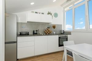 a white kitchen with white cabinets and a window at ABI Attic Apartment in Šibenik