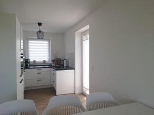 a kitchen with white cabinets and a table and chairs at Kleenes Haffhus in Ueckermünde