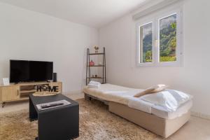 Casa da Hortência do Faial في Faial: غرفة نوم بسرير وتلفزيون وطاولة