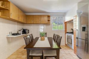 uma cozinha com uma mesa e cadeiras e um frigorífico em Casa da Hortência do Faial no Faial