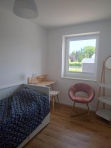 a bedroom with a bed and a chair and a window at Kleenes Haffhus in Ueckermünde