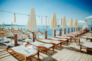 a row of chairs and umbrellas on a beach at Antalya Lara Dubleks 2+1 in Altınkum