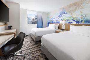um quarto de hotel com duas camas, uma secretária e uma cadeira em Courtyard New York Downtown Manhattan/Financial District em Nova Iorque