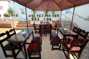 a restaurant with wooden tables and chairs and an umbrella at Hotel Rodadero Inn By GEH Suites in Santa Marta