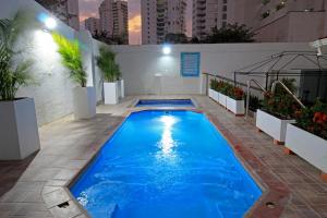 a swimming pool with blue water in a building at Hotel Rodadero Inn By GEH Suites in Santa Marta