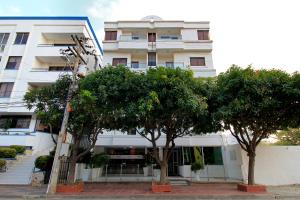 a tall white building with trees in front of it at Hotel Rodadero Inn By GEH Suites in Santa Marta