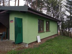 una casa verde con una puerta verde y ventanas en Zalesie z pomostem I, en Barczewo
