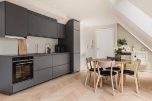 a kitchen with black cabinets and a table and chairs at Dinbnb Apartments I Mid-City Luxury with Mini Balcony and Smart TV & Sound System in Bergen