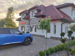 une voiture bleue garée devant une maison dans l'établissement Мотель "КАЛИНА", à Yavoriv