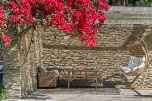 a table and chairs under a brick wall with red flowers at The Secret Valley of Chora - 5 mins to Beach in Livádhia