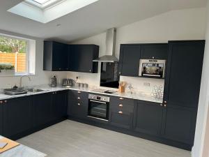 La cuisine est équipée de placards noirs et d'un four avec plaques de cuisson. dans l'établissement Hugo House, à Poole