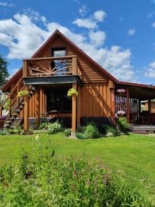 eine große Holzhütte mit Veranda und Rasenfläche in der Unterkunft Žalioji in Paduyelis