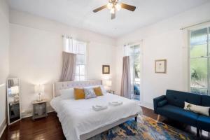 a white bedroom with a bed and a blue couch at The Mardis Gras Manor Walkable, Historic, Local Treasure in Mobile
