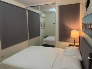 a bedroom with a bed and a lamp and a mirror at Casa Maria 2BR Apt with terrace in Levittown